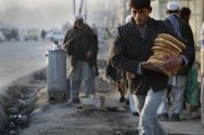 An Afghan man walks with bread as a roadside tea seller is seen in ...