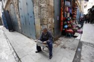 An Egyptian reads a new paper as he sits at an empty street usually ...