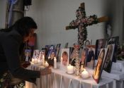 A woman lights a candle among pictures of slain Iraqi Christians at ...