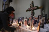 A woman lights a candle among pictures of slain Iraqi Christians at ...