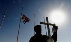 A soldier polishes the cross on a memorial at Camp Bastion in ...