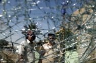 Iraqis are seen through a shattered windshield of a vehilce at the ...