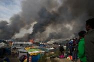 migrants-look-at-burning-makeshift-shelters-and-tents-in-the-calais-jungle-during-the-october-evacuation