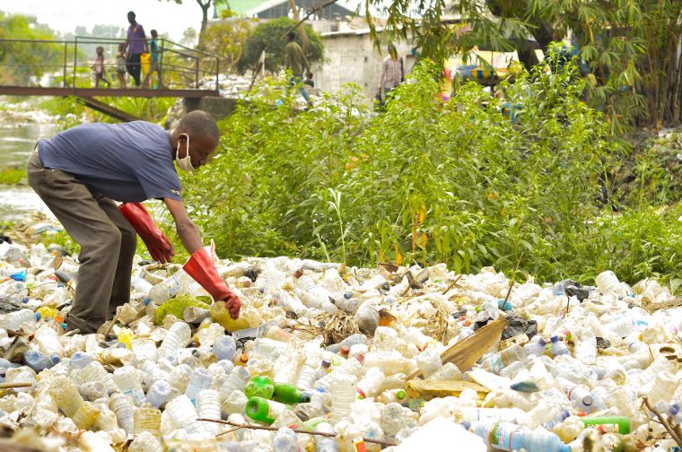 A waste picker collecting plastic from the river in the Democratic Republic of Congo.